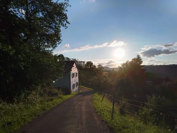 Ländliche Zufahrt mit Haus im Sonnenuntergang