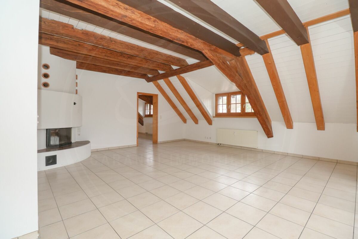 Großer leerer Wohnraum mit sichtbaren Holzbalken