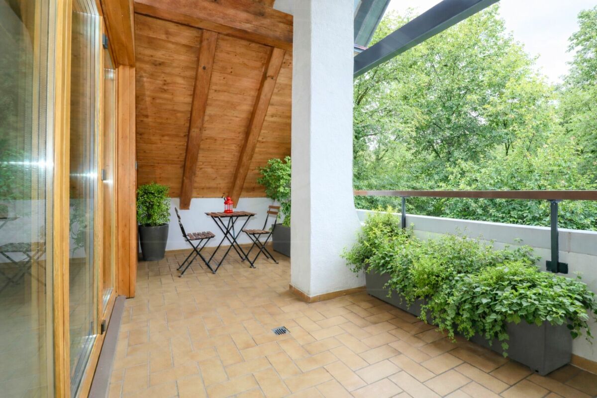 Überdachter Balkon mit Holzdecke und Grünblick