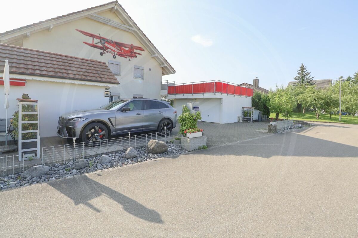 Außenansicht eines Wohnhauses mit Sportwagen und Garten