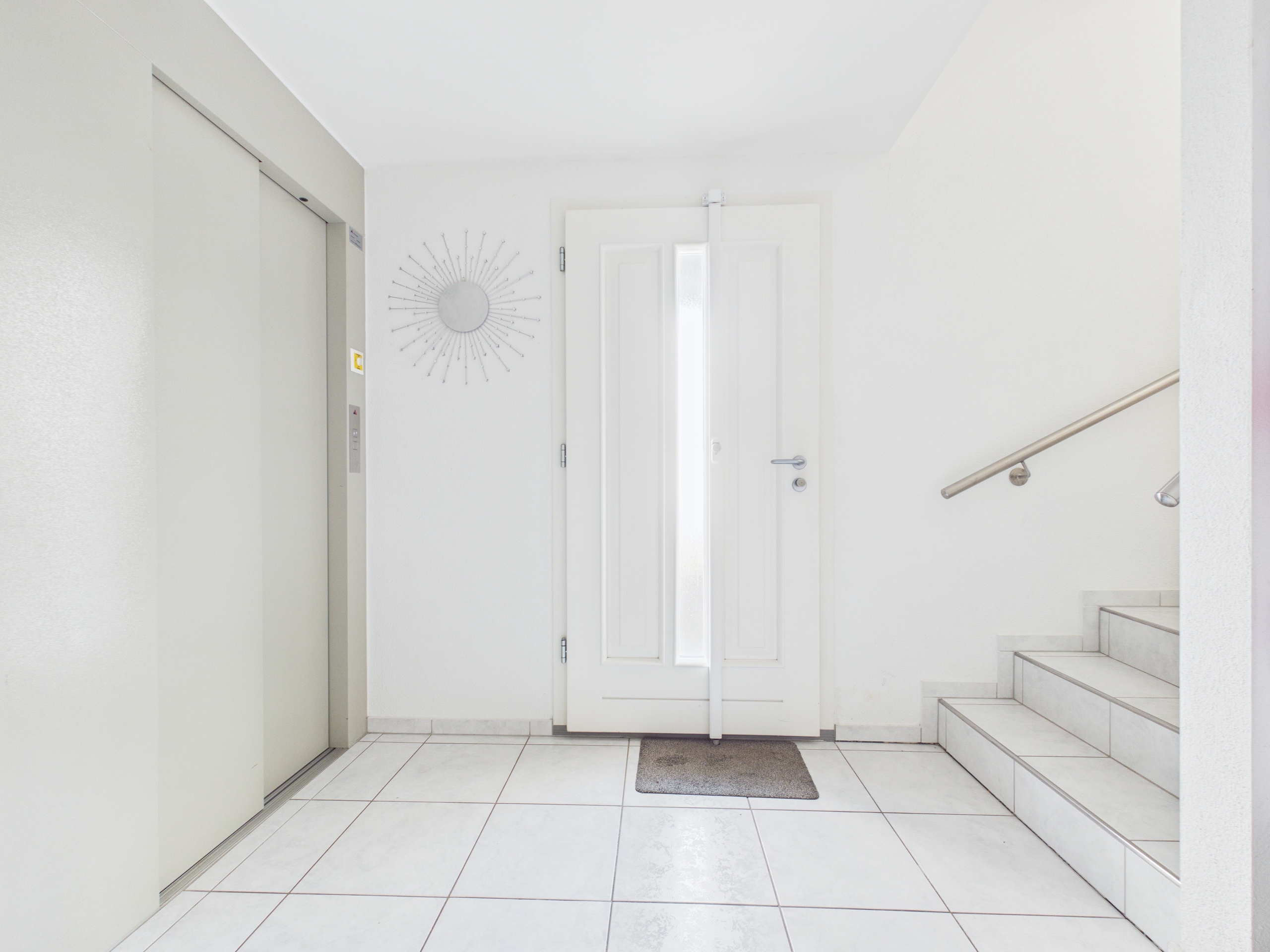 Heller Eingangsbereich mit Treppe und Aufzug
