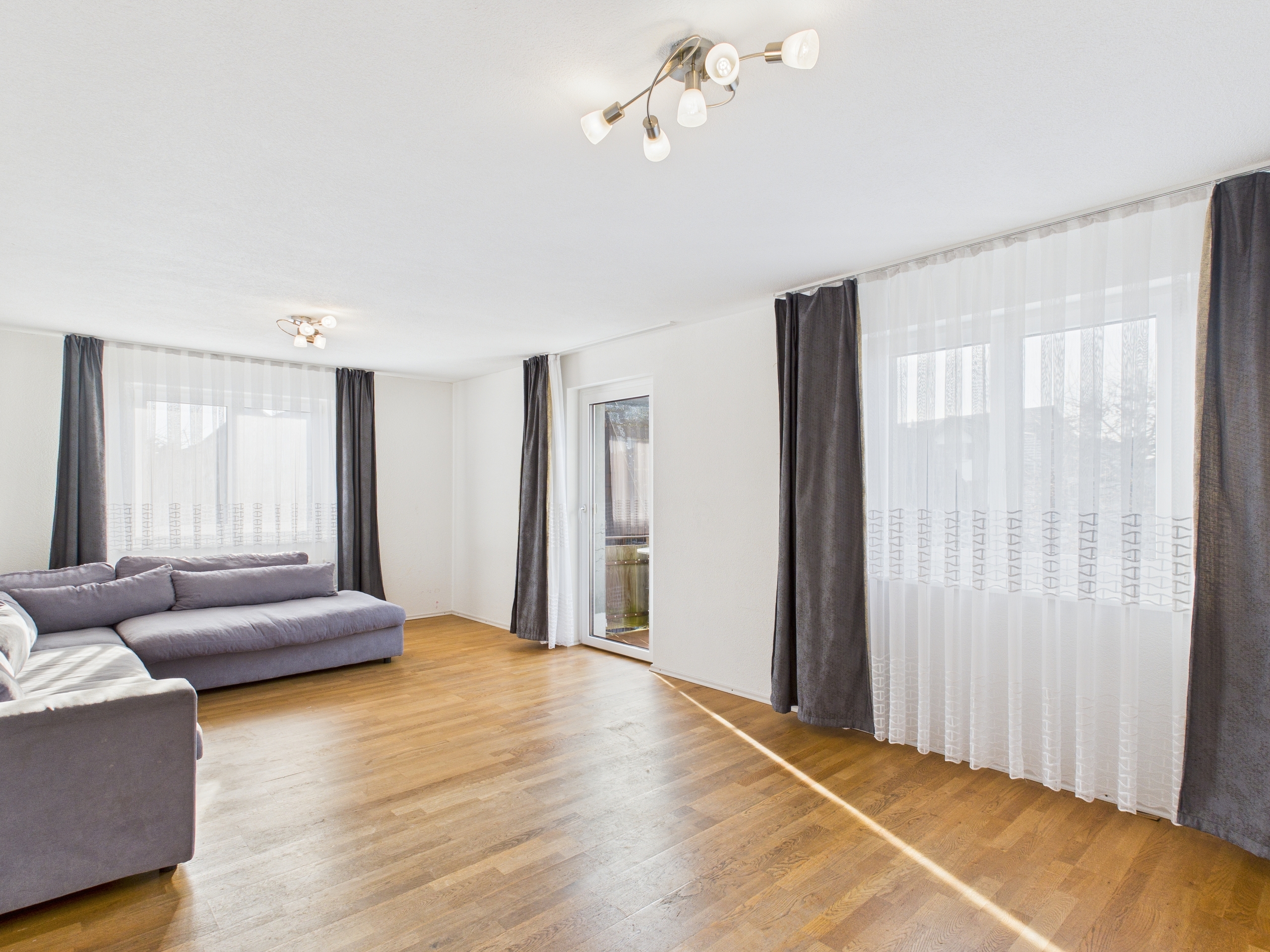 Heller Wohnraum mit Ecksofa und großen Fenstern