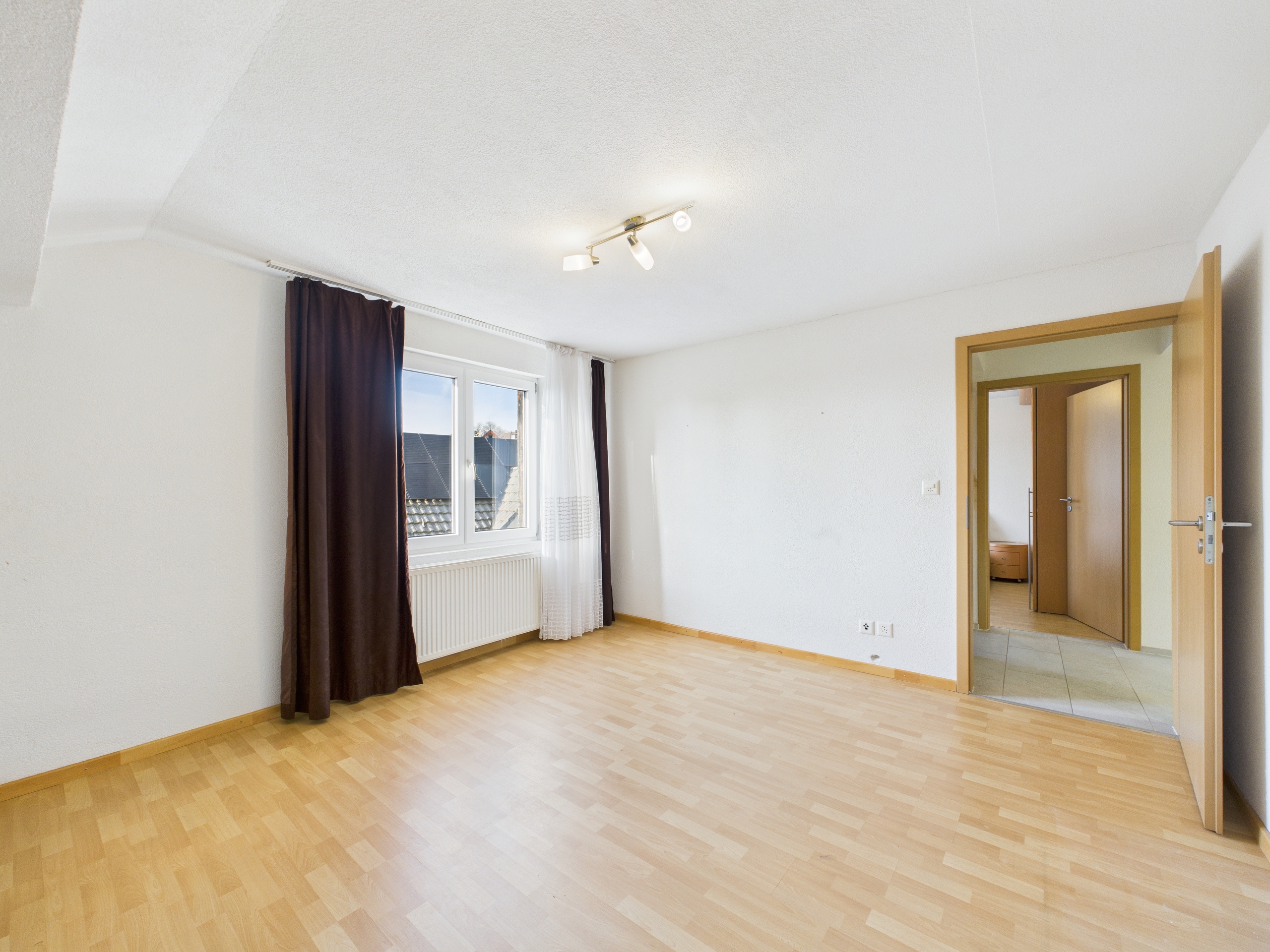 Helles, leeres Schlafzimmer mit Fenster und Flurzugang