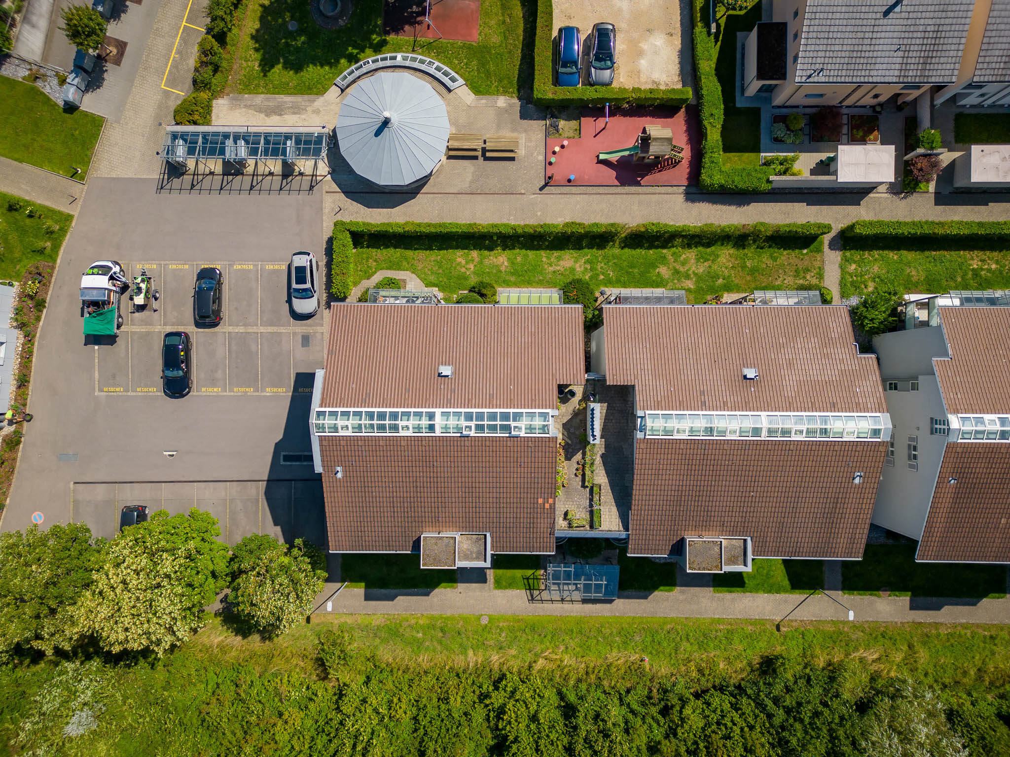 Luftaufnahme eines Wohnquartiers mit Reihenhäusern, Parkplätzen und Grünflächen