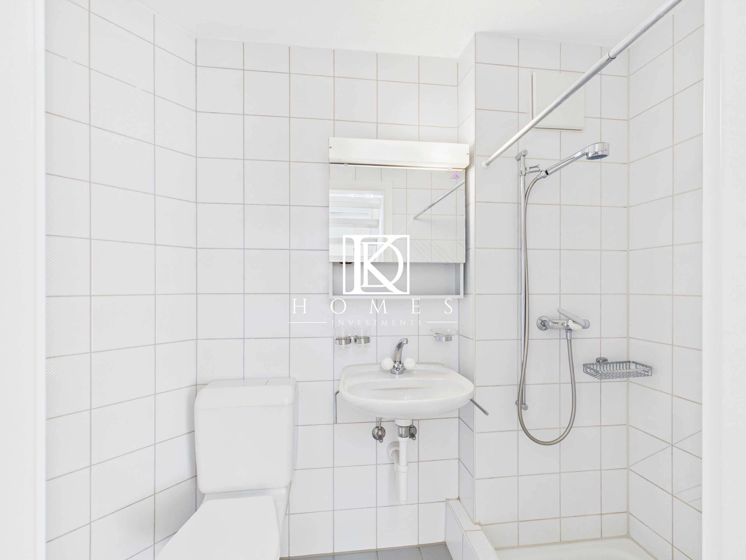 Kleines weiß gefliestes Badezimmer mit Dusche und WC