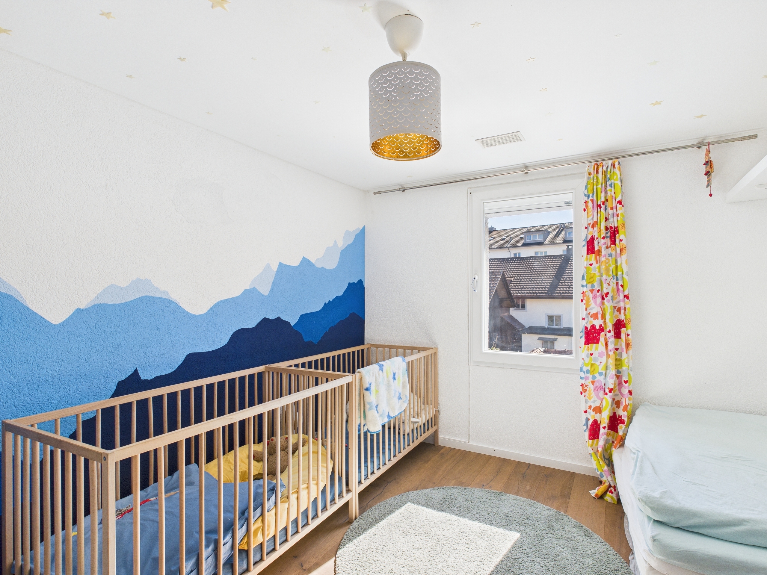 Kinderzimmer mit Kinderbett und Bergwandmotiv