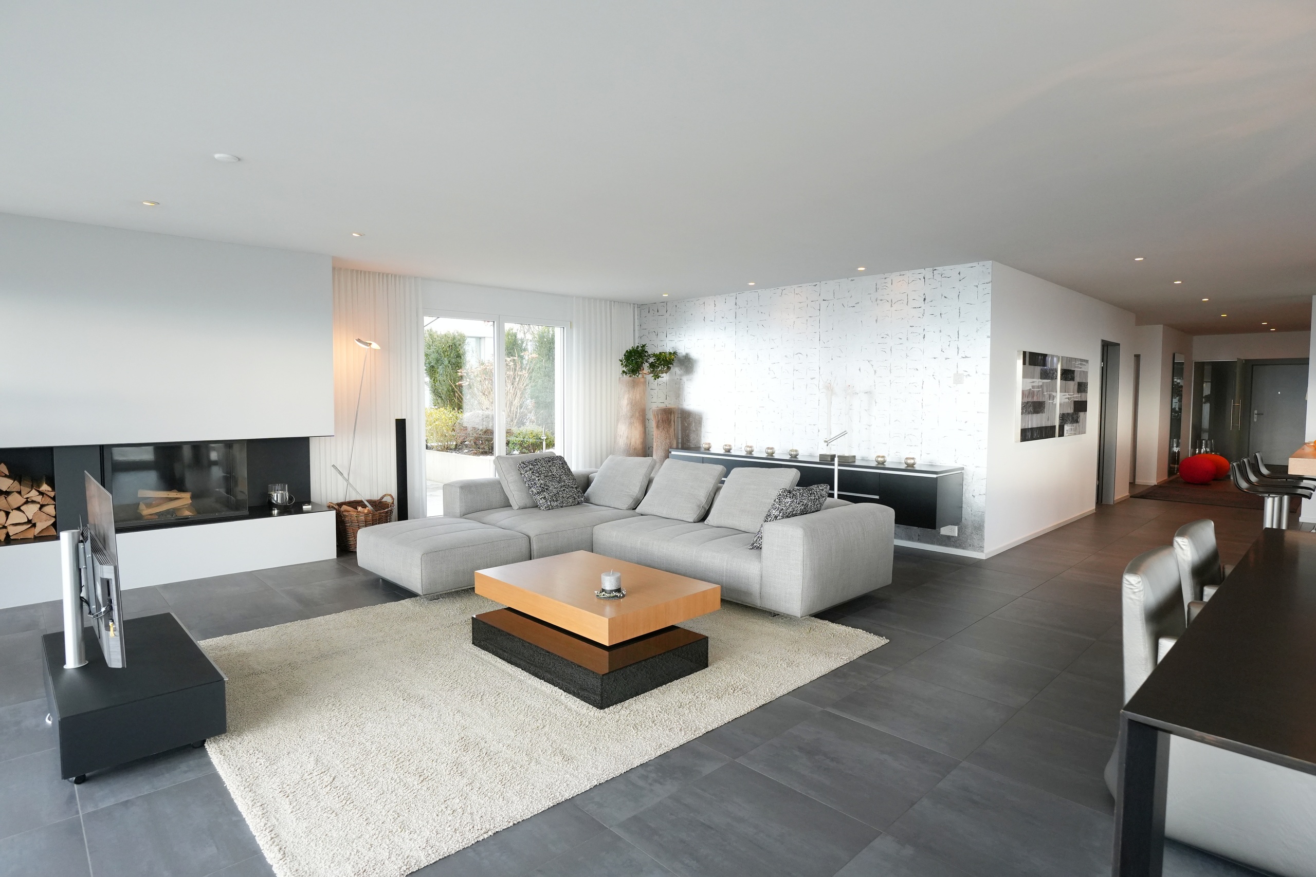 Modernes, offen gestaltetes Wohn-Esszimmer mit Kamin und großer Sofalandschaft