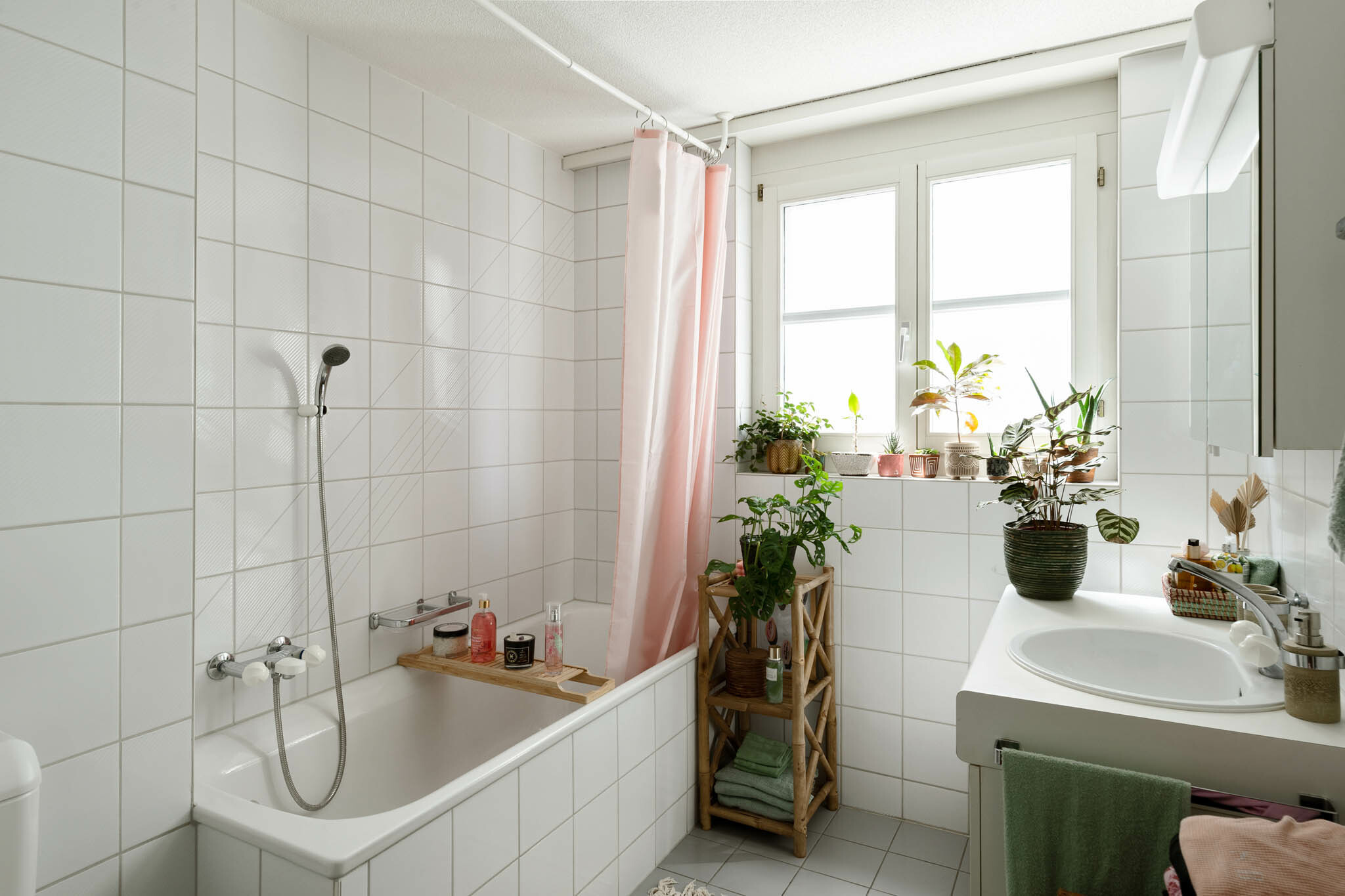 Helles Badezimmer mit Badewanne, Fenster und Pflanzen