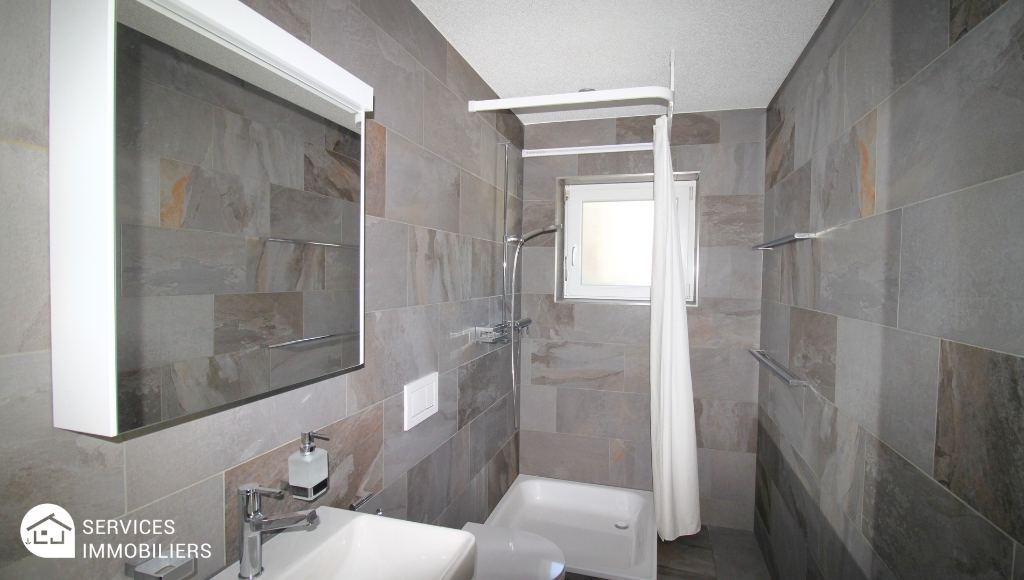 Modernes graues Badezimmer mit Dusche und Waschbecken