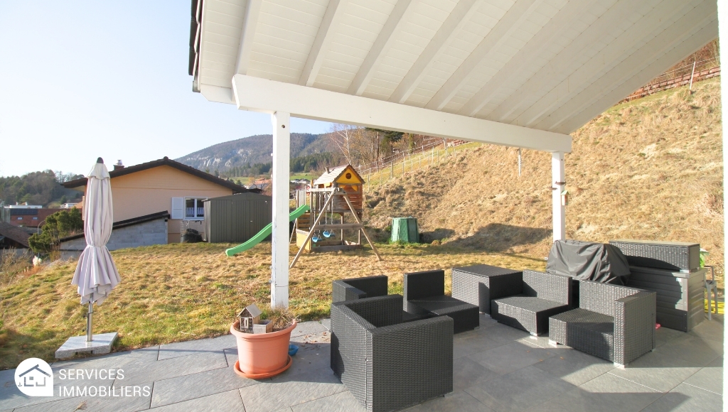 Überdachte Terrasse mit Lounge-Möbeln und Gartenbereich