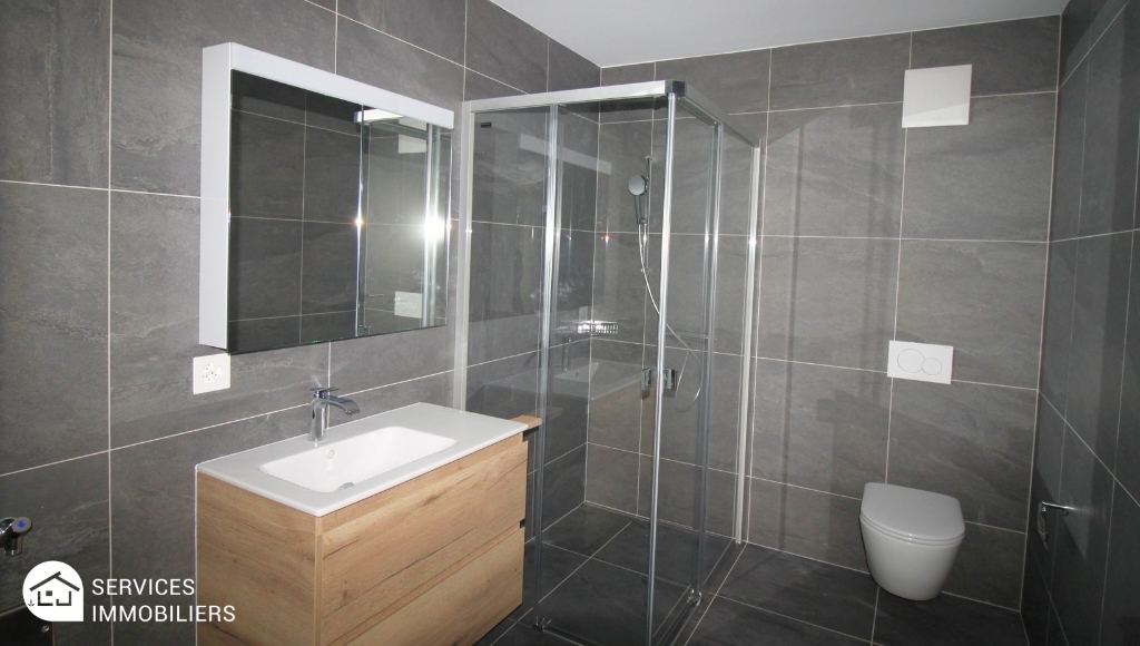 Modernes Badezimmer mit dunklen Fliesen und Glasdusche
