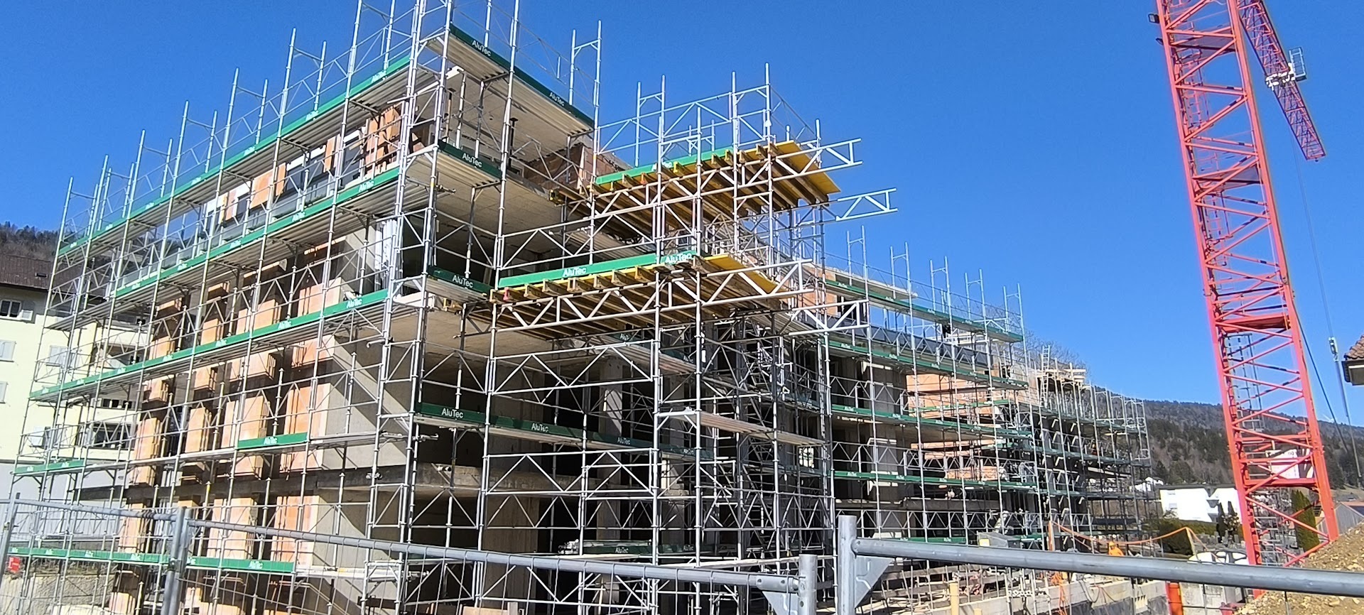 Mehrfamilienhaus im Bau mit Gerüst und Kran