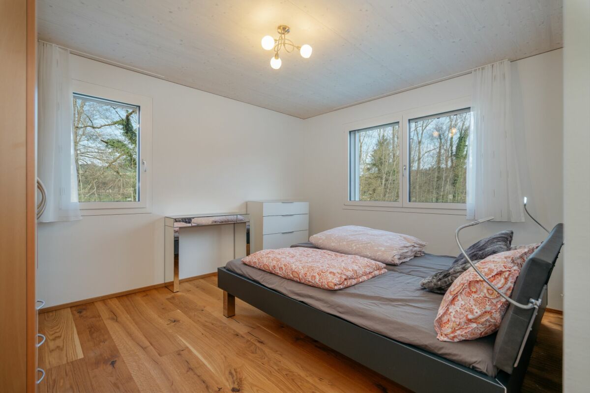 Helles Schlafzimmer mit Doppelbett und zwei Fenstern