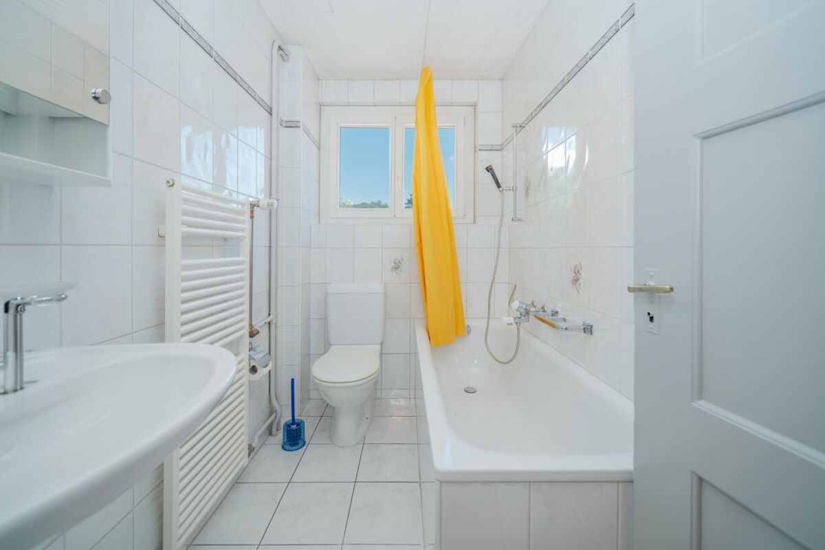 Kleines weißes Badezimmer mit Badewanne und WC