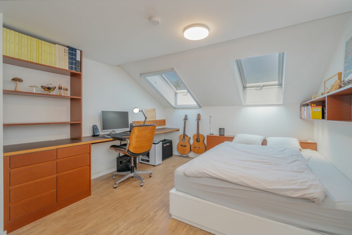 Dachzimmer mit Bett und Arbeitsbereich