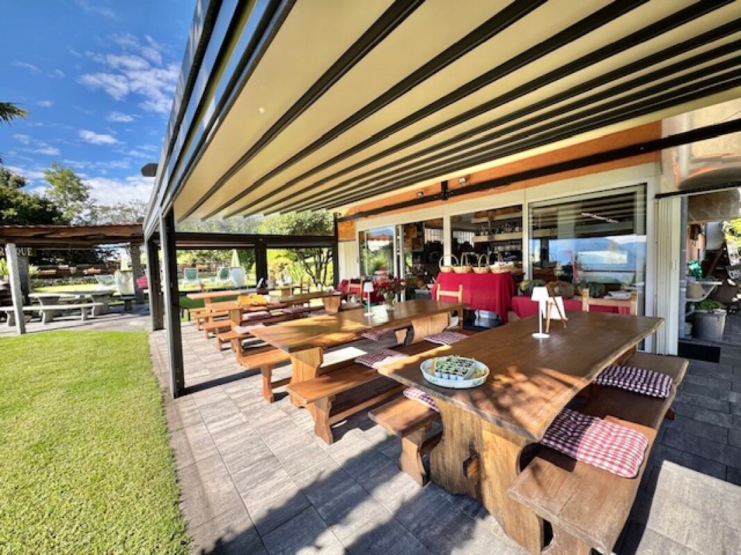 Überdachte Terrasse mit großen Holztischen