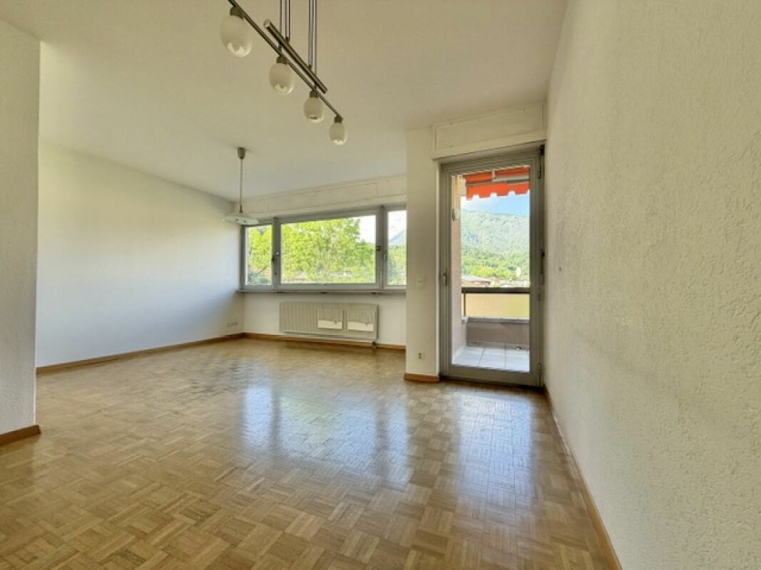 Heller leerer Wohnraum mit Balkon und Bergblick