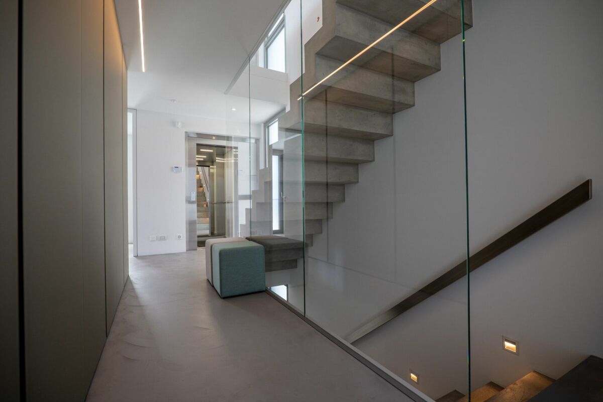 Moderner Flur mit Betontreppe und Glasgeländer