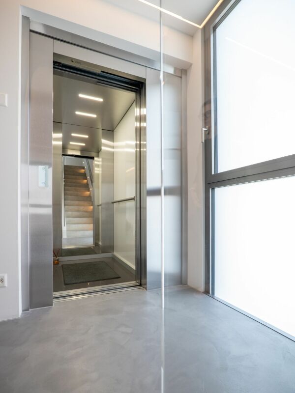 Moderner Eingangsbereich mit Aufzug und Treppe im Hintergrund