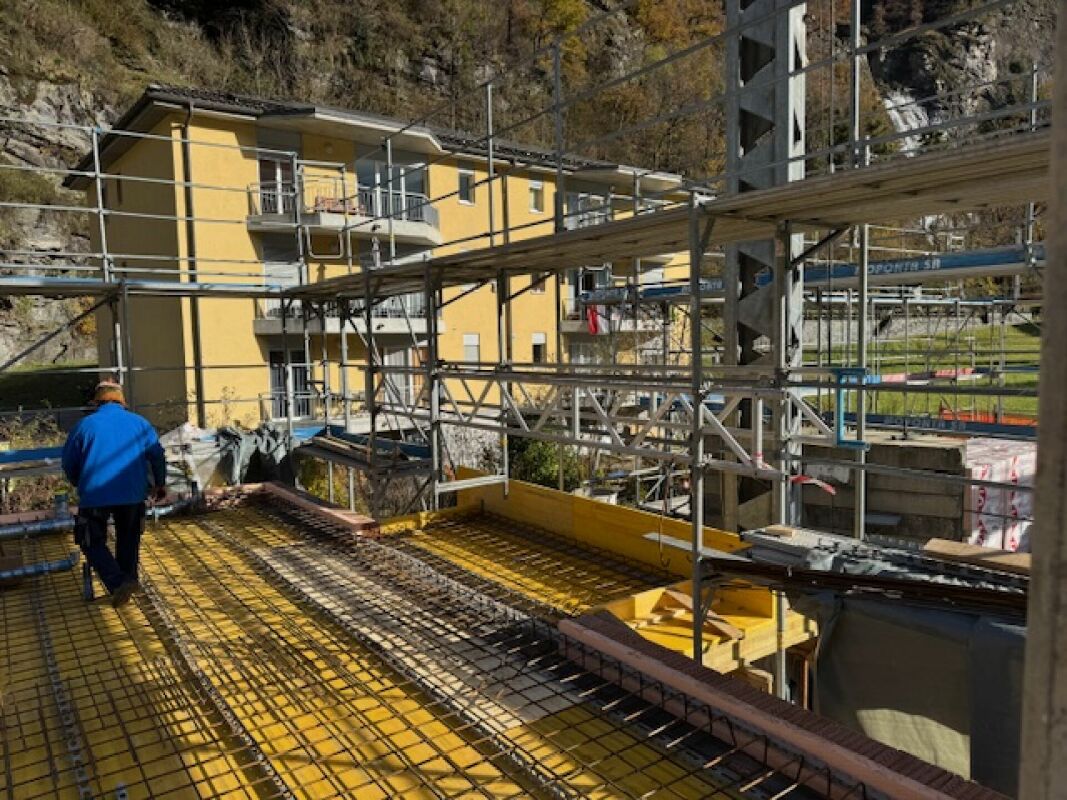 Baustelle mit Gerüst vor gelbem Wohngebäude