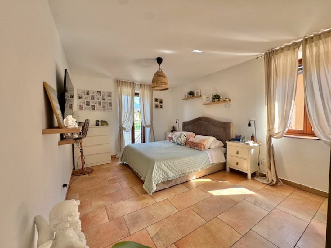 Helles Schlafzimmer mit Terrakottafliesen und zwei Fenstern