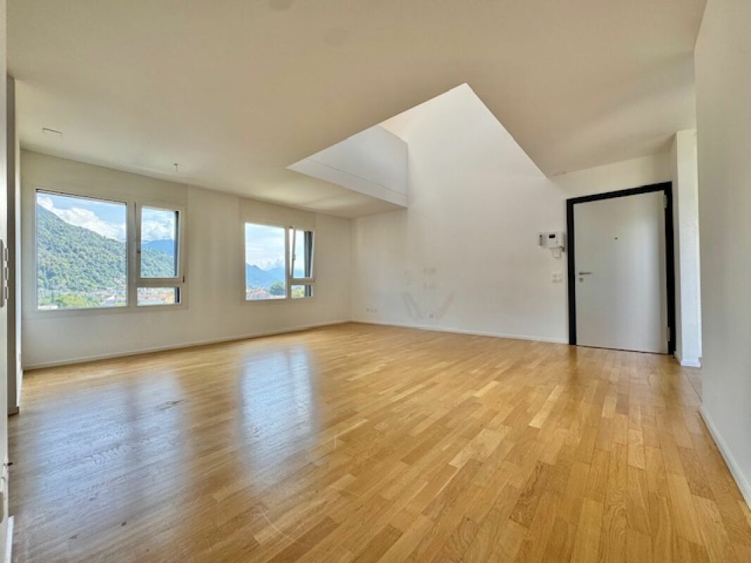 Heller leerer Wohnraum mit Dachfenster und Bergblick