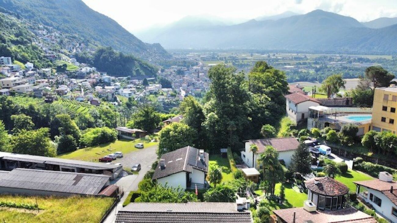 Panoramablick über ein Tal mit Wohngebiet und Bergen