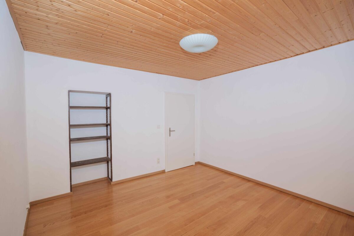 Leerer Wohnraum mit Holzdecke und Einbauregal