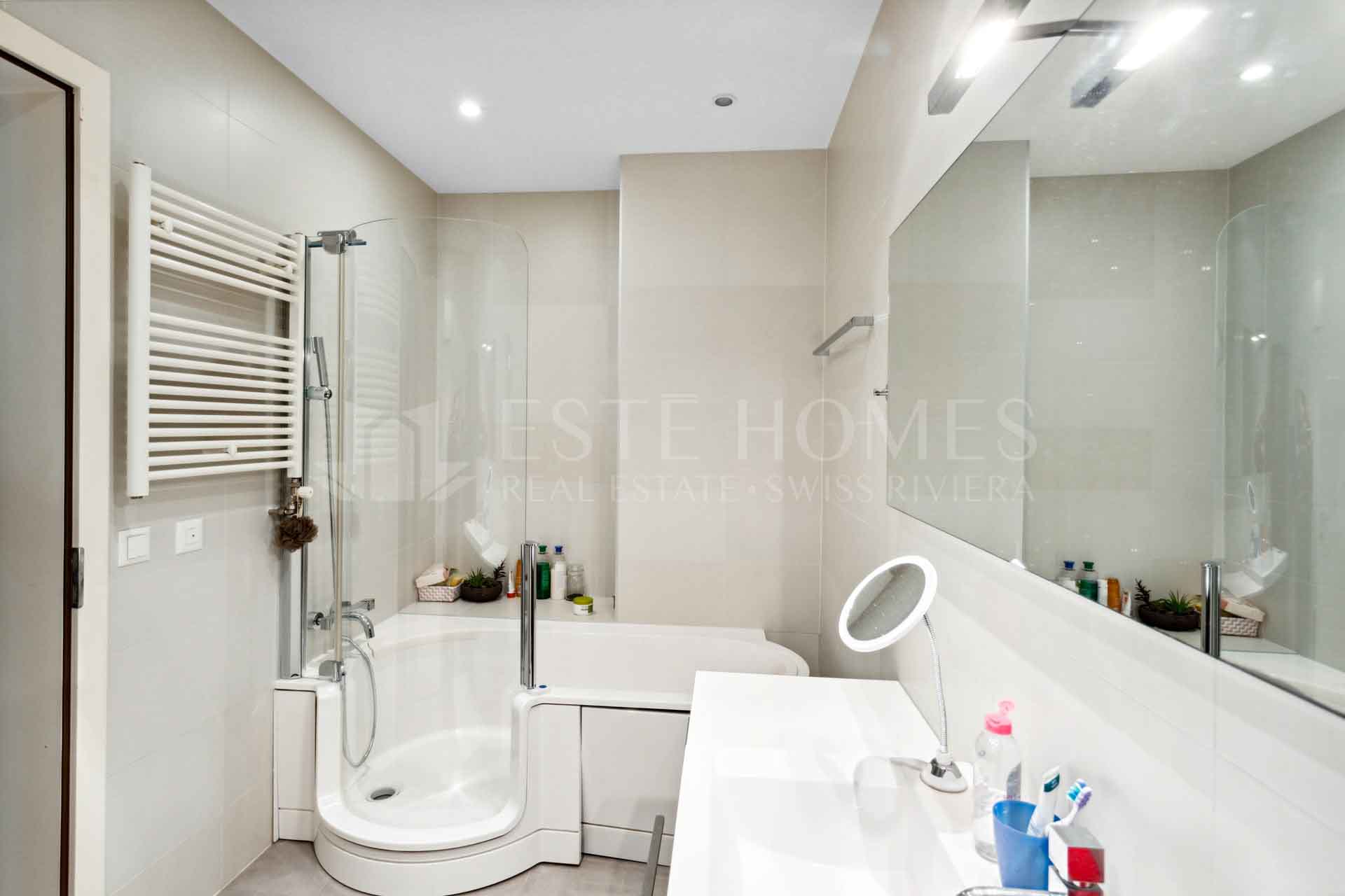 Modernes Badezimmer mit Badewanne und großer Spiegelwand