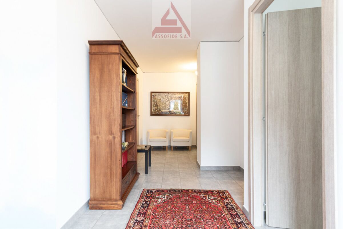 Heller Flur mit Holzvitrine und roten Teppichläufer