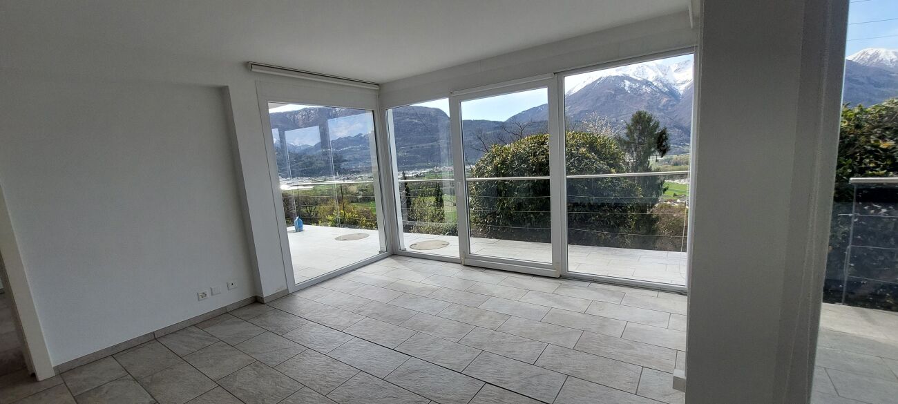Leerer, heller Wohnraum mit Panoramafenstern und Bergblick