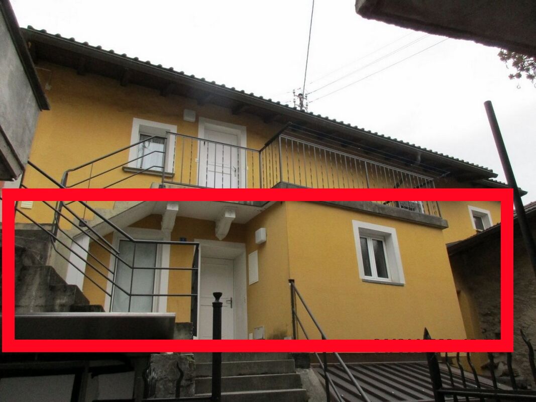 Außenansicht eines gelb verputzten Wohnhauses mit Treppen und Balkon
