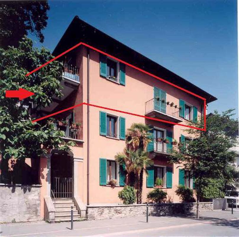 Mehrfamilienhaus mit Balkonen und grünen Fensterläden