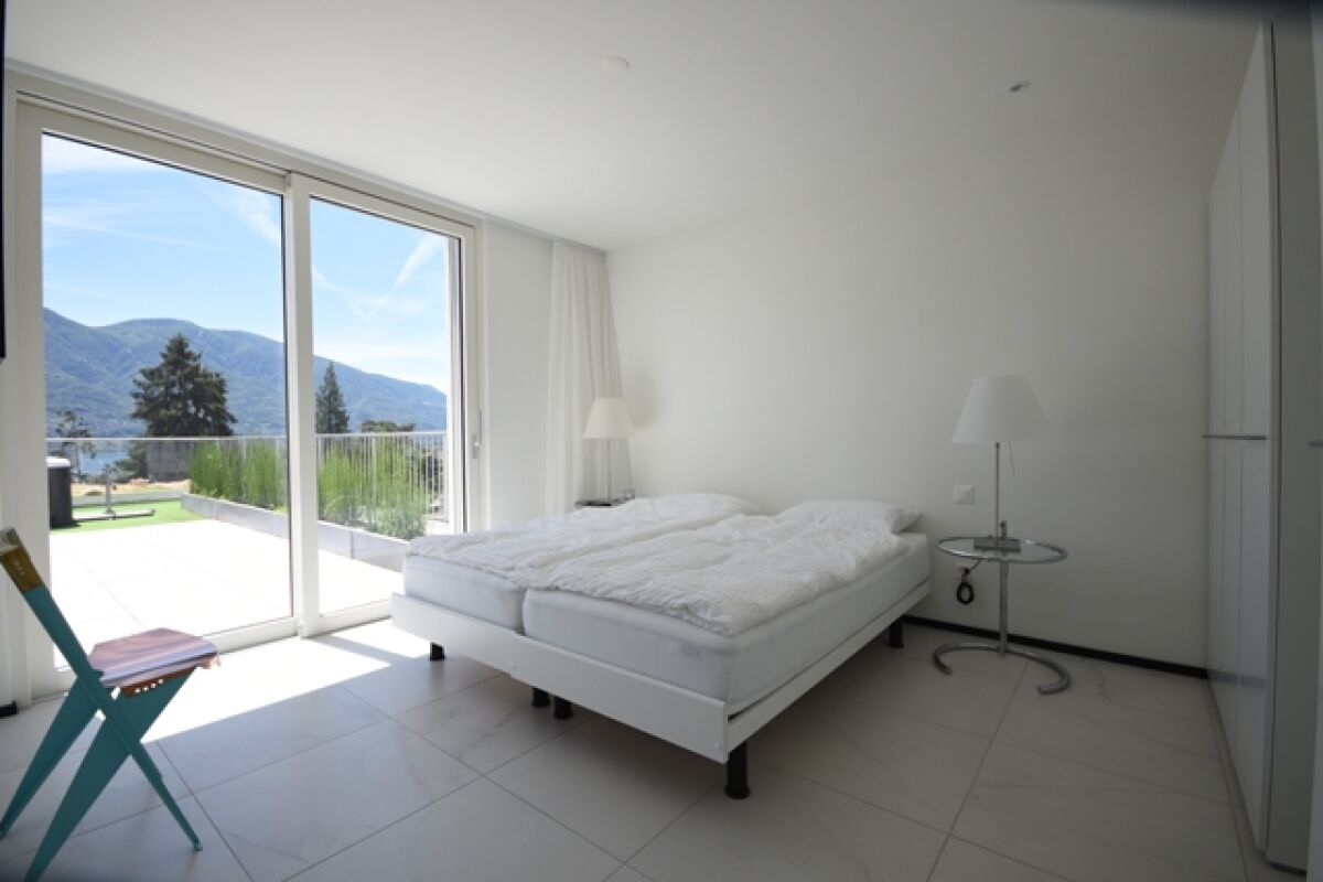 Helles Schlafzimmer mit großer Glasfront und Bergblick