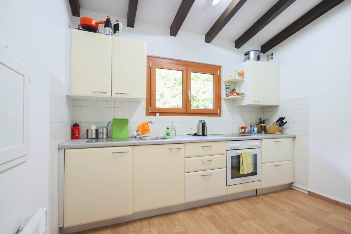 Helle Küche mit Holzfenster und sichtbaren Deckenbalken