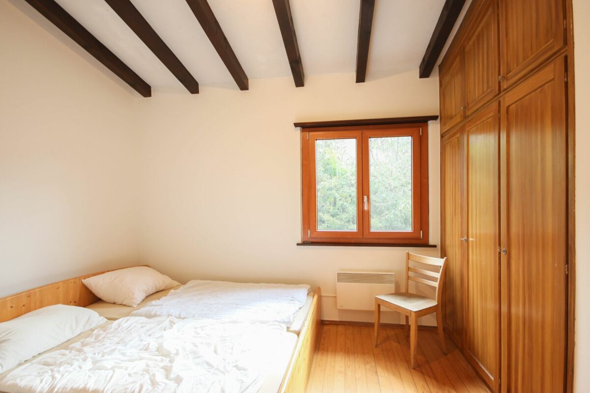 Helles Schlafzimmer mit Holzmöbeln und sichtbaren Deckenbalken