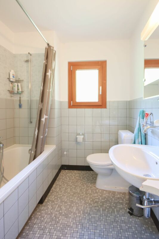 Badezimmer mit Badewanne, WC und Fenster