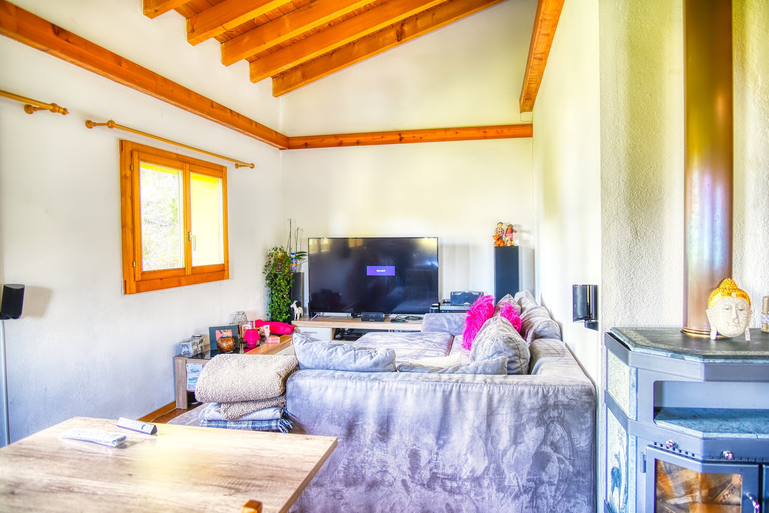 Gemütliches Wohnzimmer mit sichtbaren Holzbalken und Holzofen