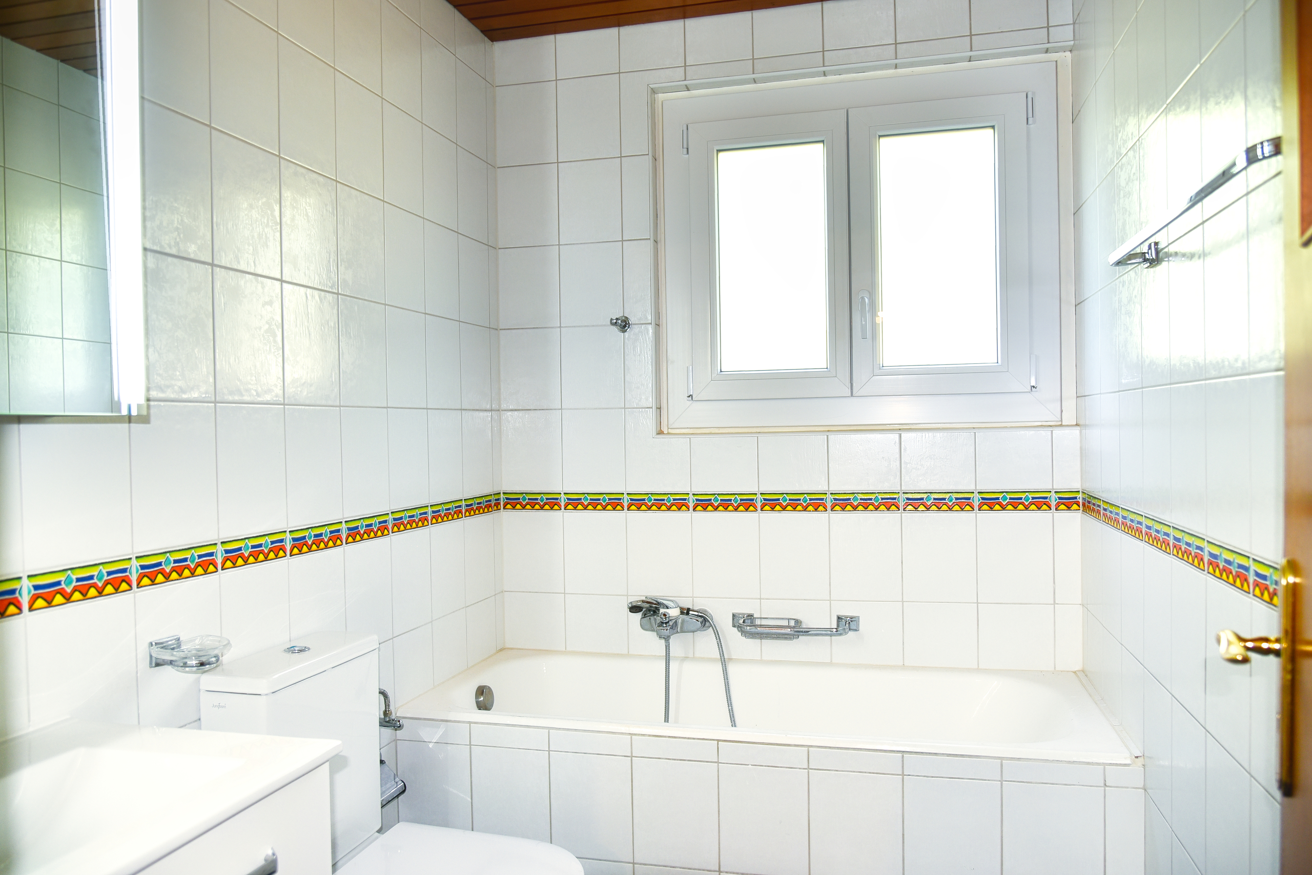 Kleines weiß gefliestes Bad mit Badewanne