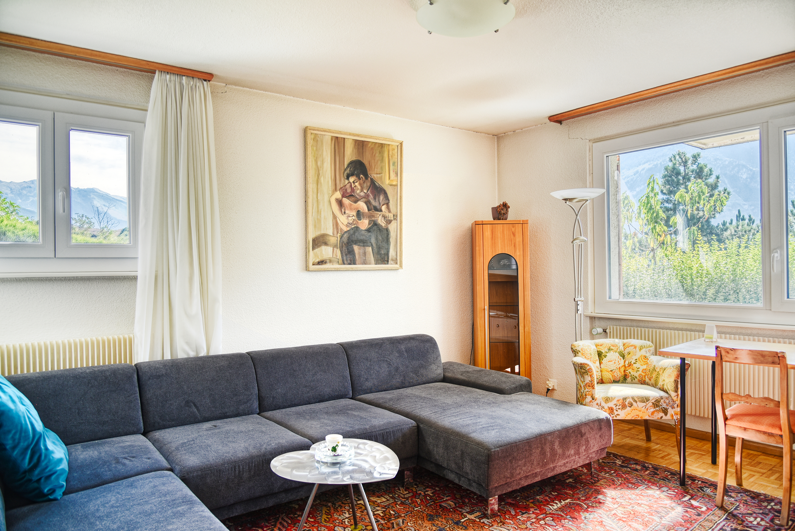 Helles Wohnzimmer mit Ecksofa und Bergblick