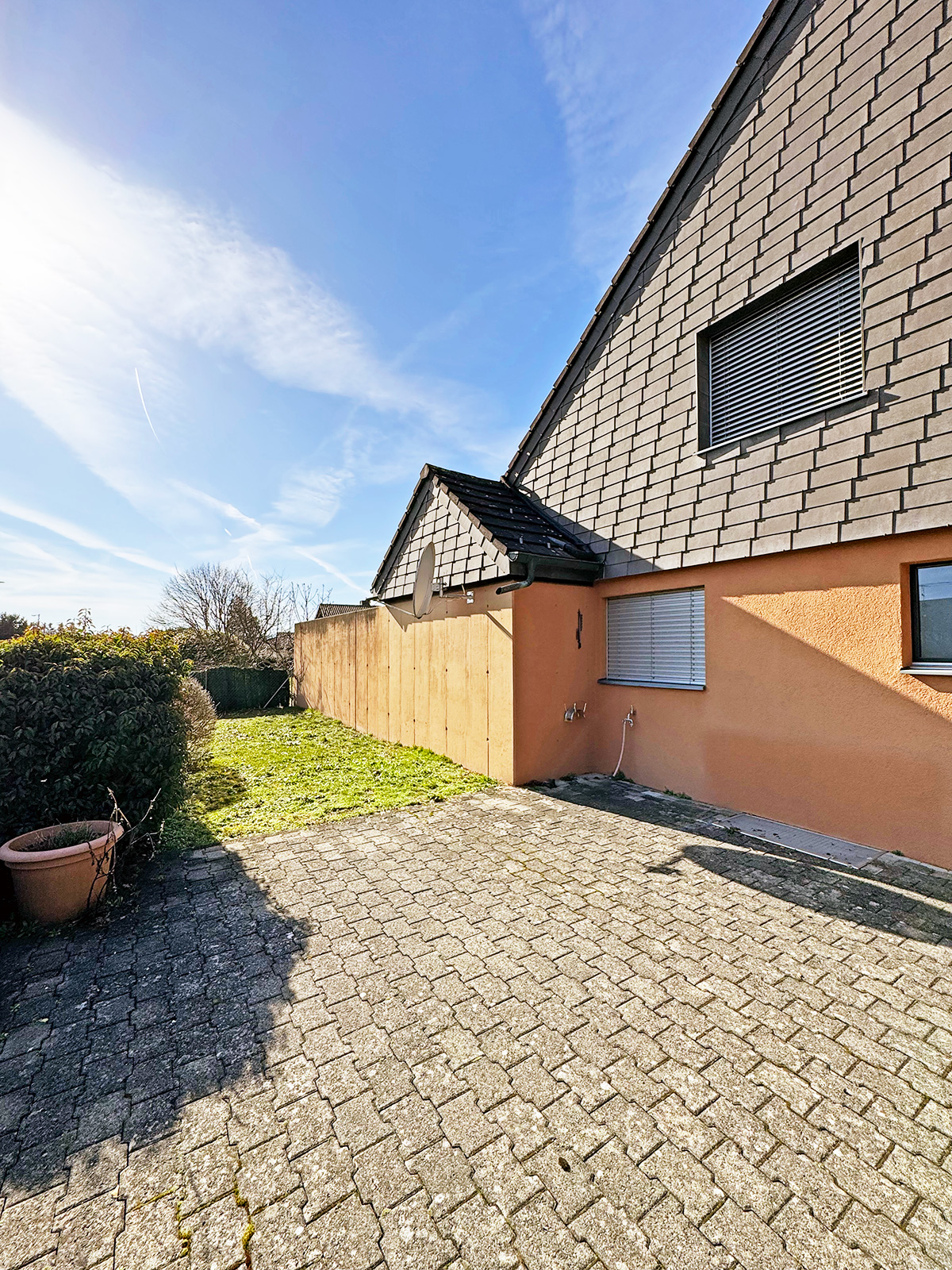 Außenbereich mit Hausfassade und gepflasterter Terrasse