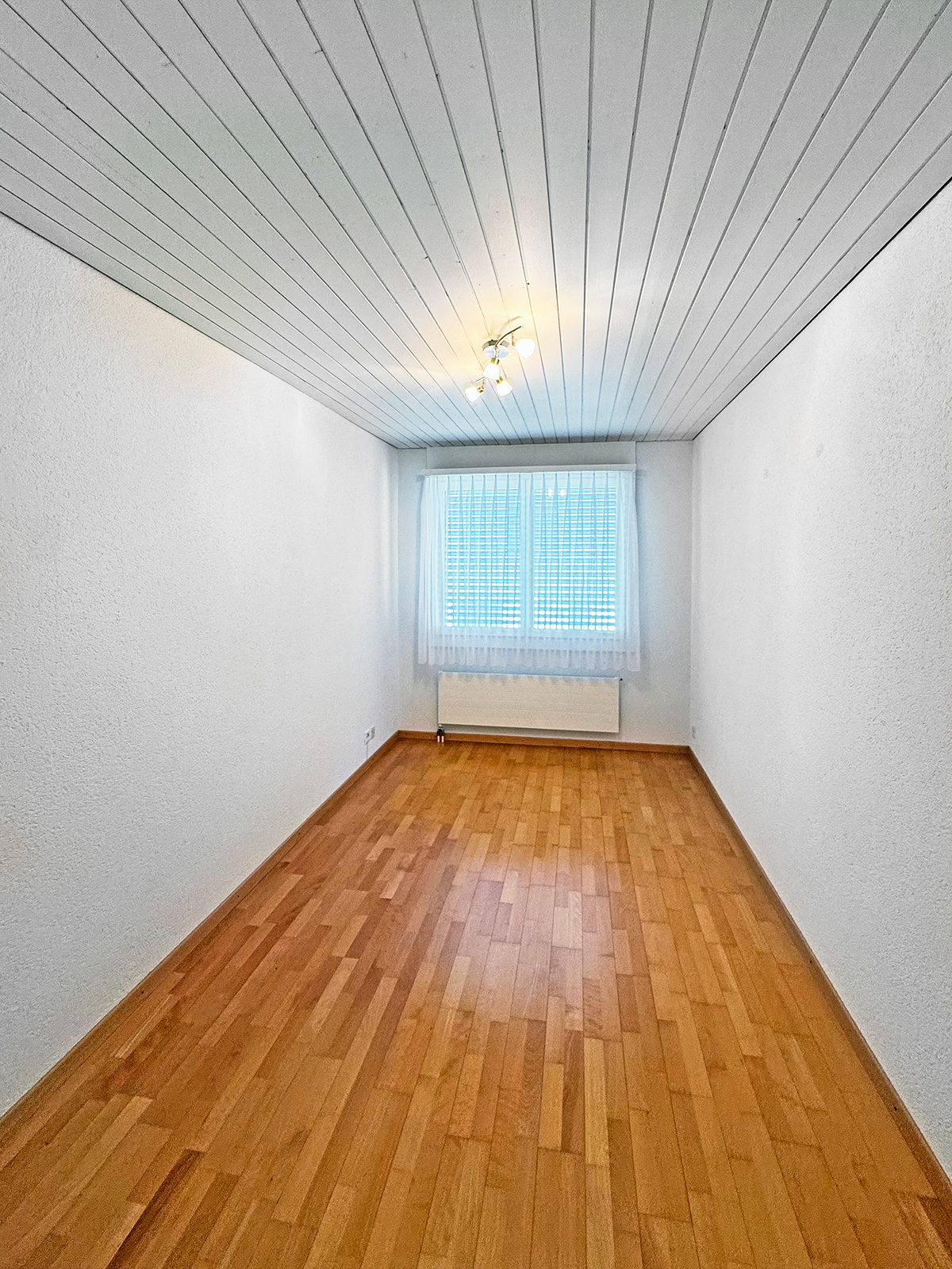 Schmaler, leerer Raum mit Holzfußboden