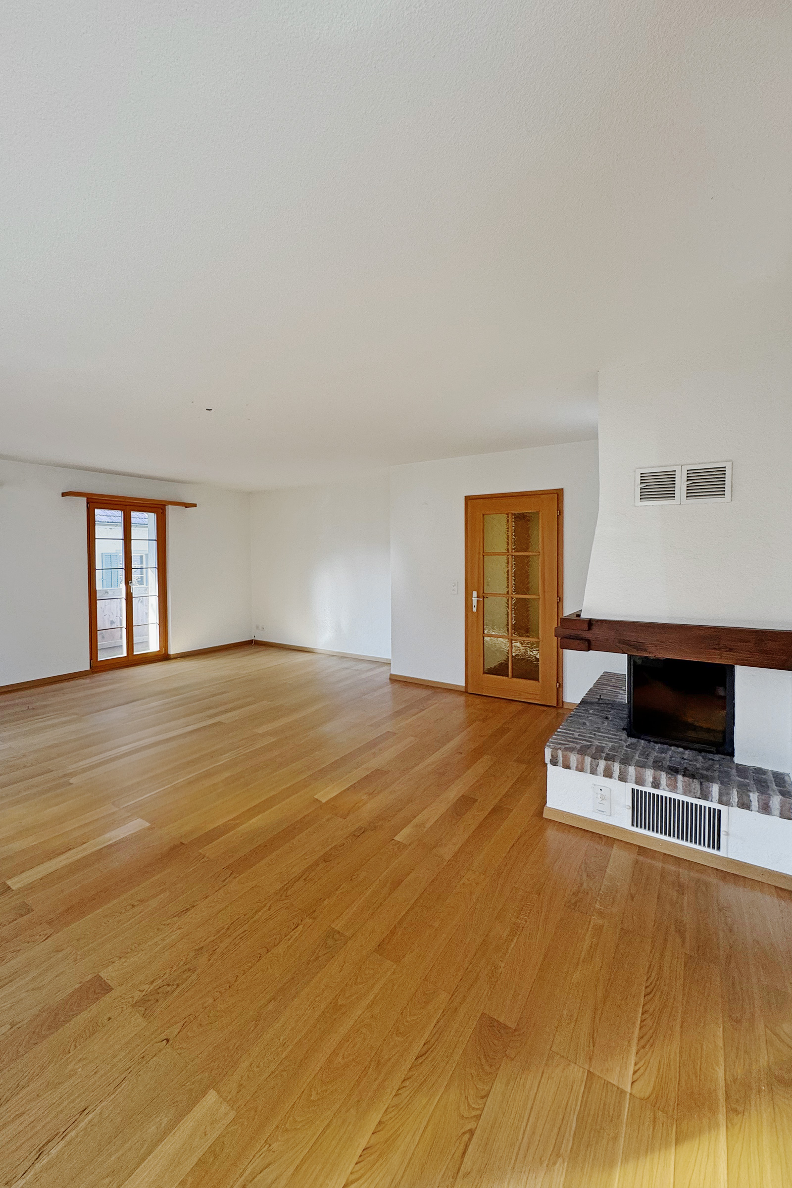 Leerer Wohnraum mit Kamin und Holztüren