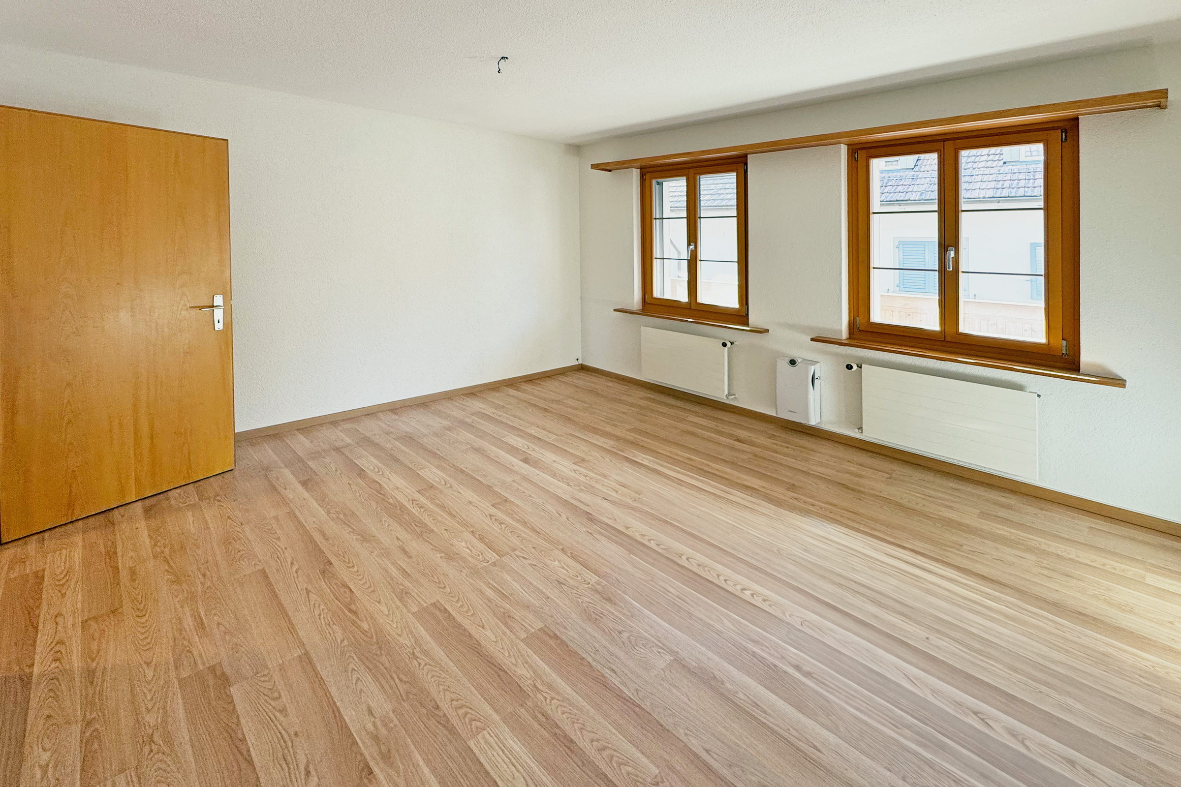 Leerer heller Wohnraum mit Parkett und Holzfenstern
