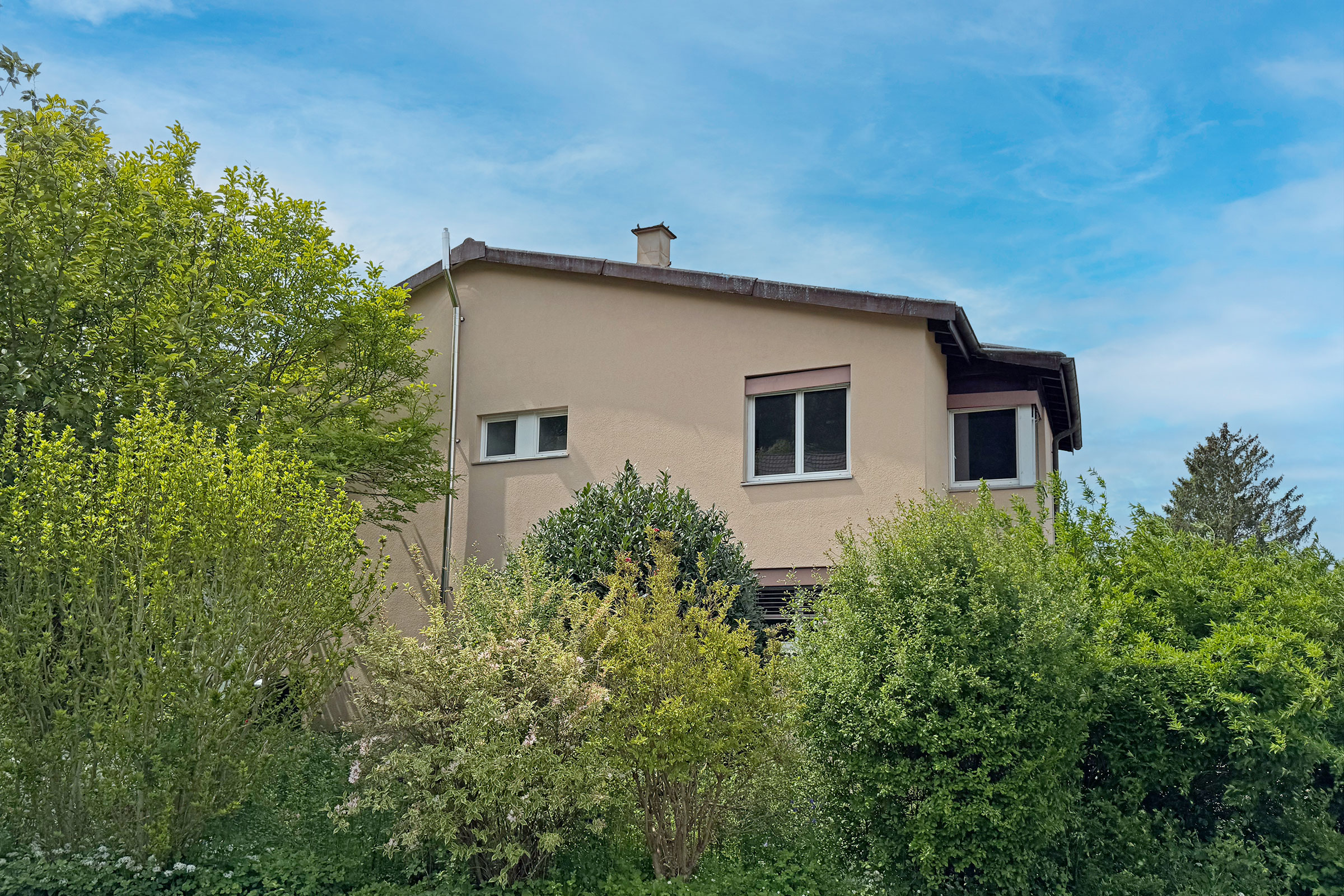 Beiges Wohnhaus mit Gartenansicht