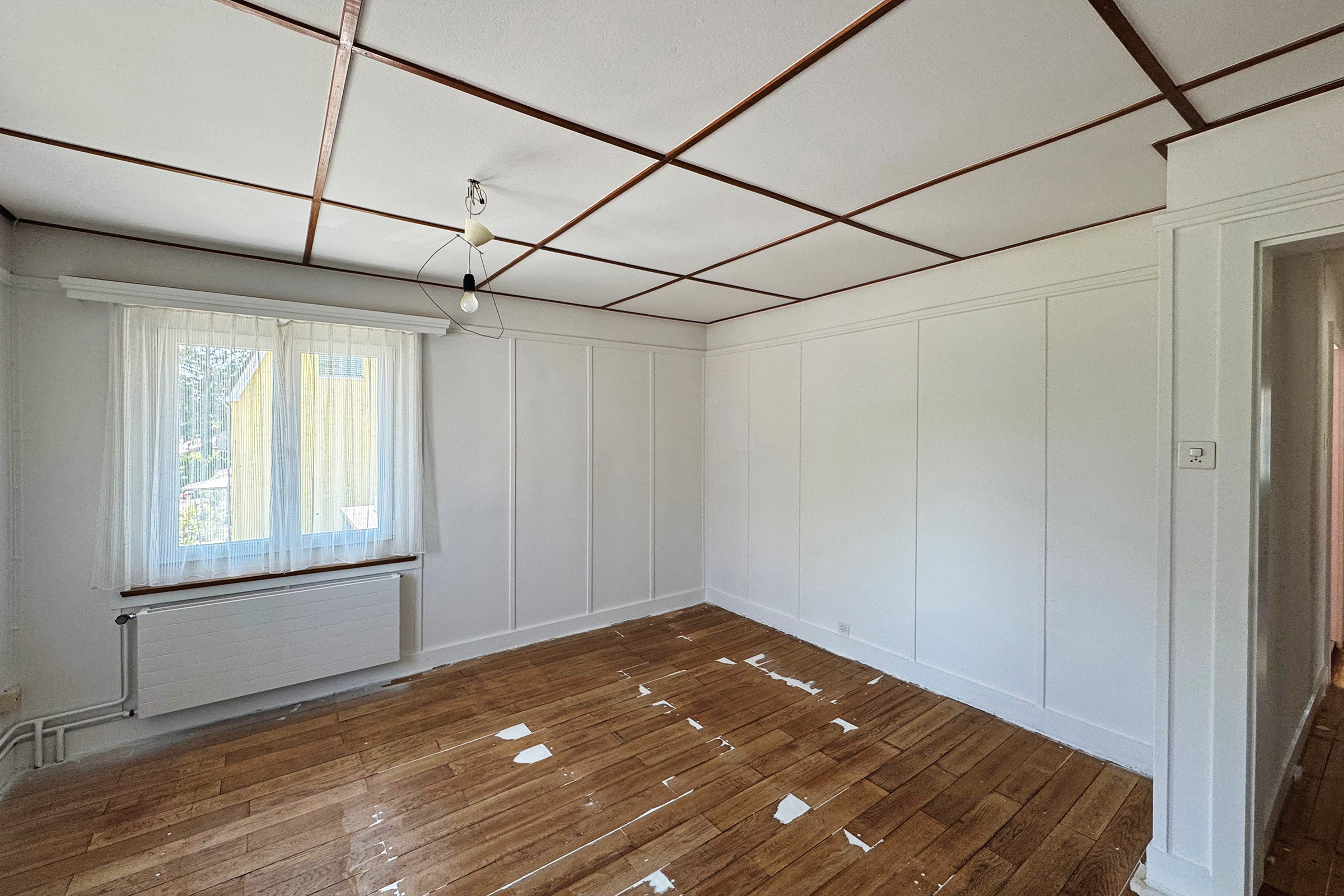 Leerer Wohnraum mit Holzdecke und Parkettboden