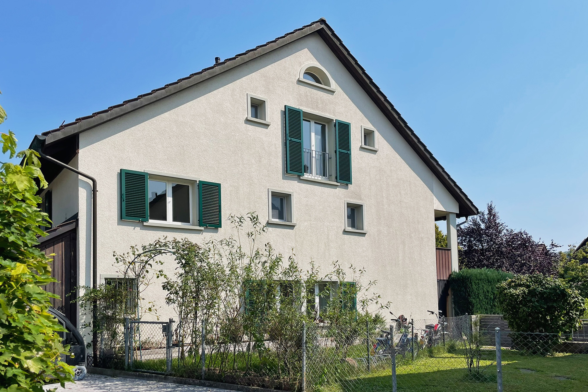 Einfamilienhaus mit Satteldach und grünen Fensterläden