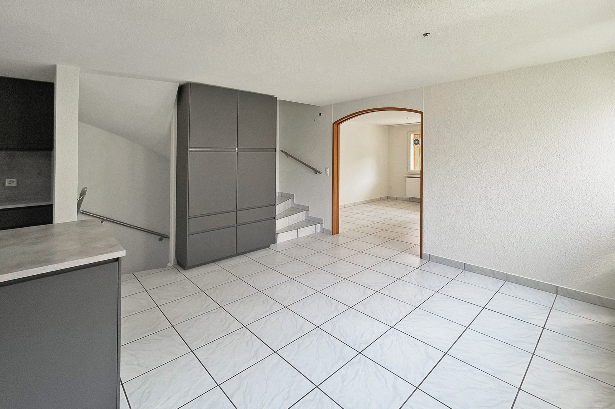 Heller Wohnbereich mit Treppe und Rundbogenöffnung