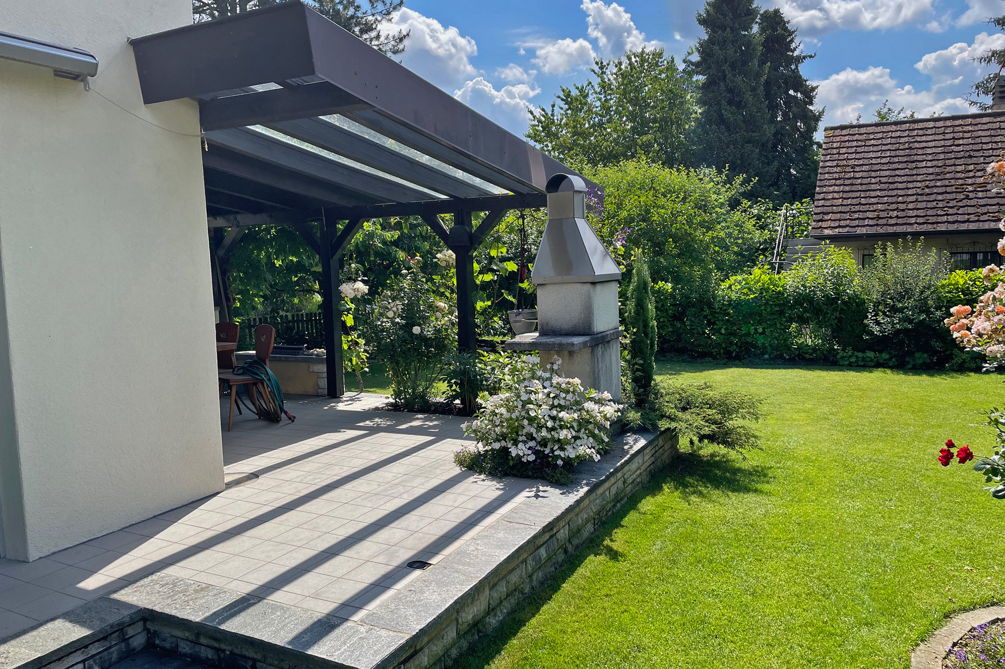 Überdachte Terrasse mit Garten und Grillkamin