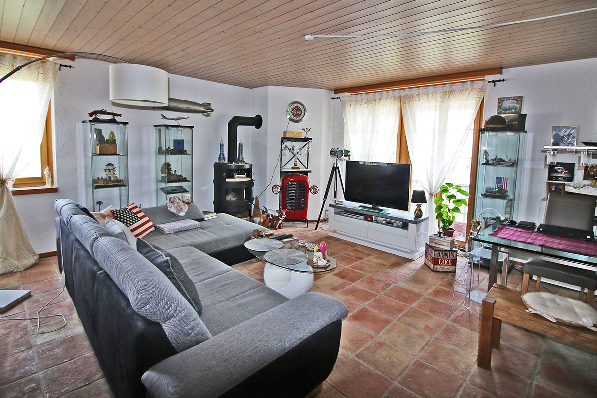 Gemütliches Wohnzimmer mit Ofen, Fernseher und Ecksofa